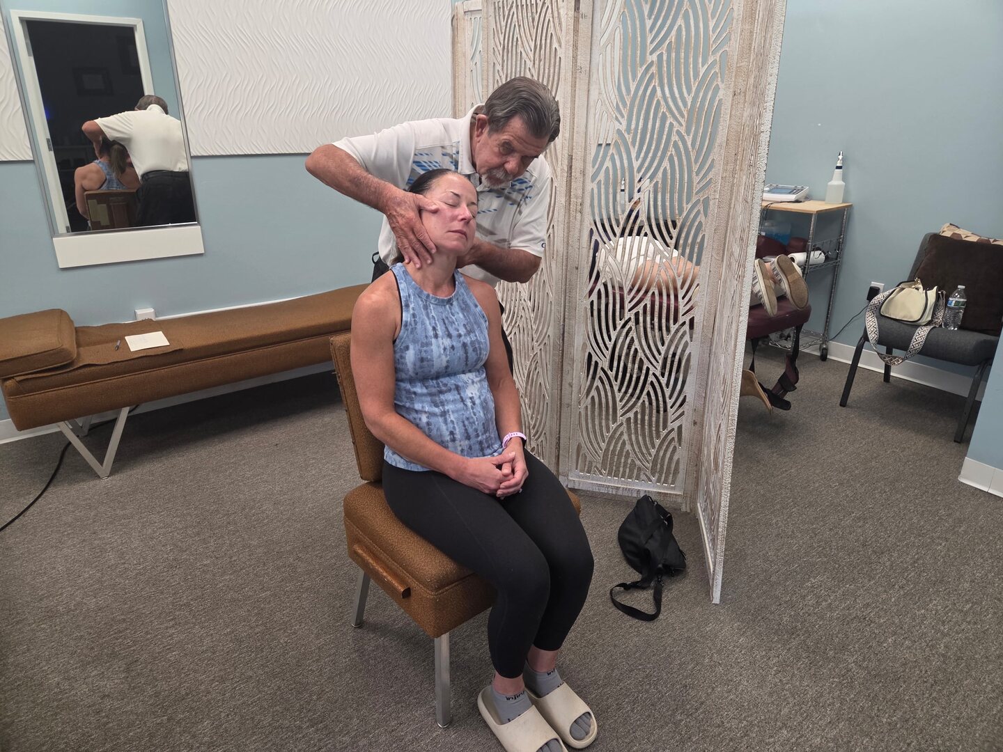 Dr. Wuotila performing a seated neck adjustment on a patient in the treatment room.